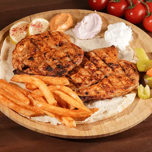 Farooj chicken diet meal with french fries, sauce, tomatoes, lemon and a bread underneath it